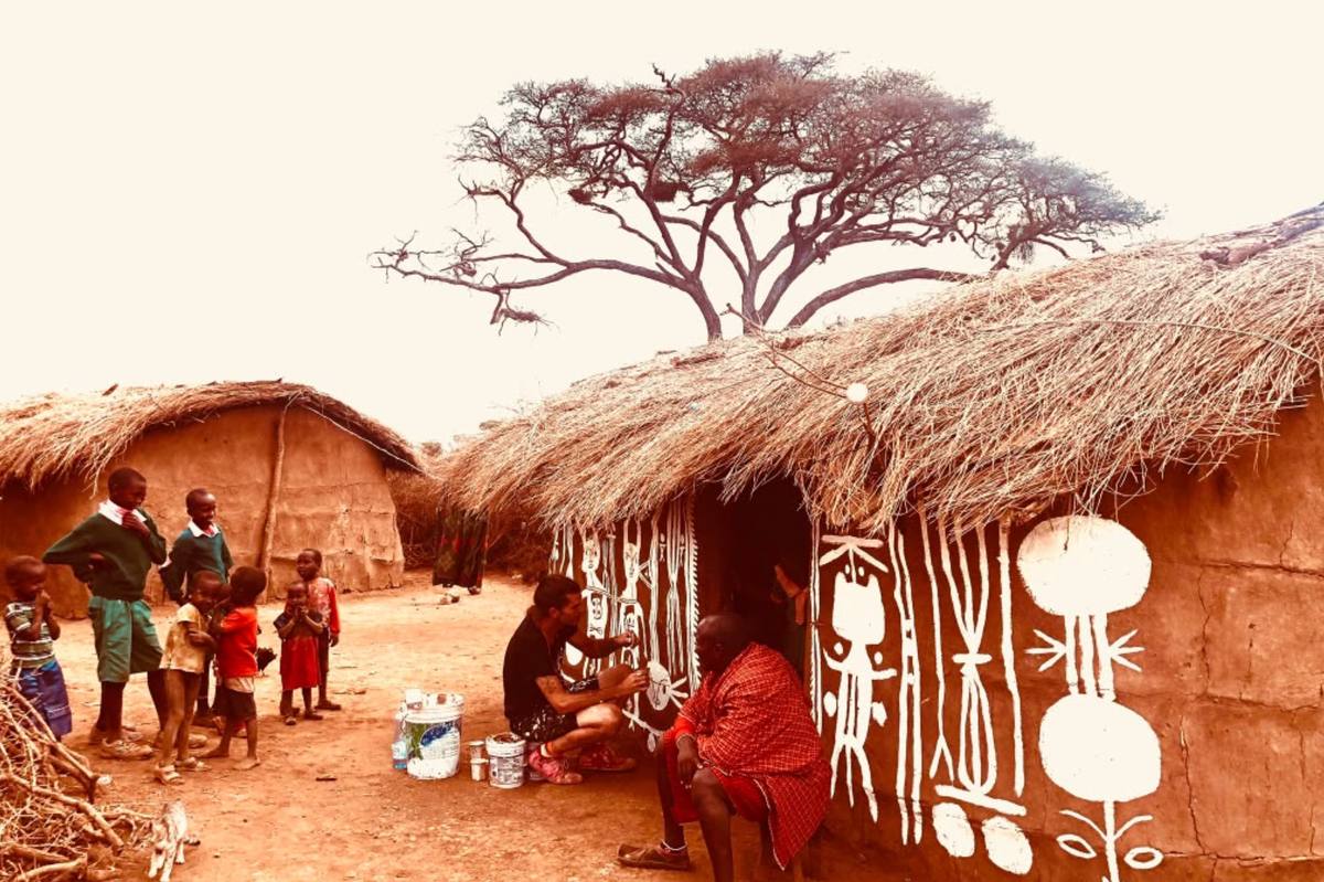 The artist at work on a homestead wall beneath an acacia