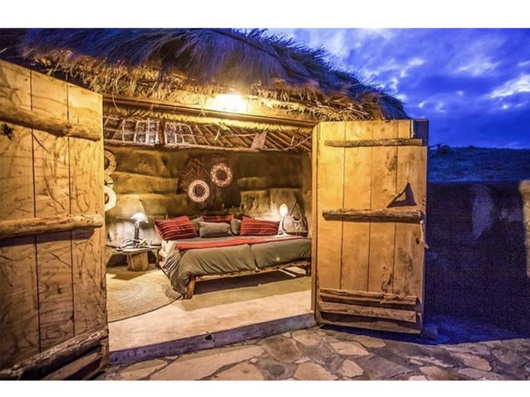 A boma at dusk, its door open on a bed inside
